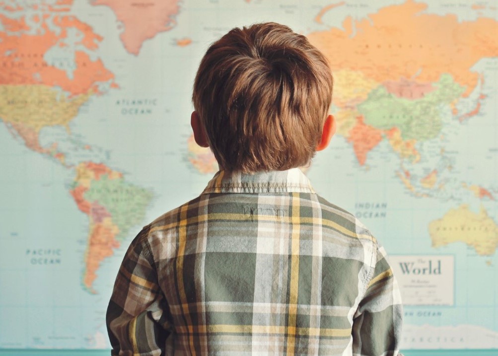 young boy looking at a world map